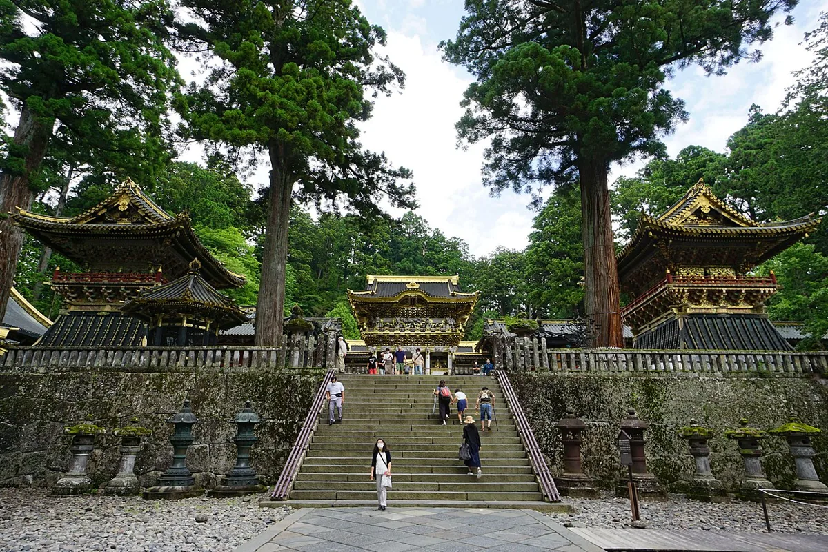 Stone steps and Yomeimon framed by trees at Nikko Toshogu